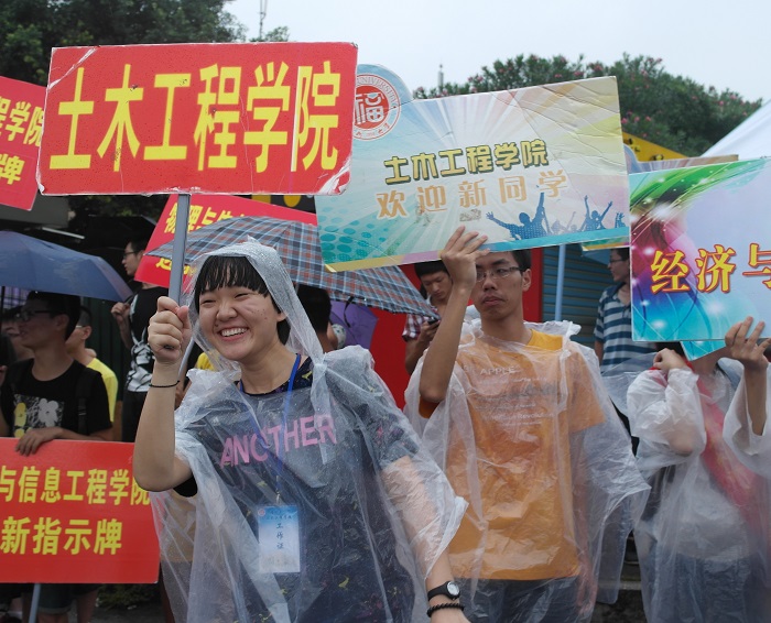4迎新人员在西门身披雨衣迎接本科新生的到来